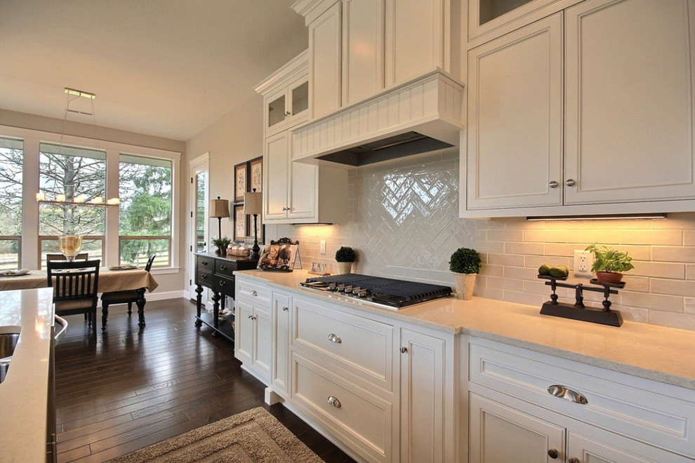 Open concept kitchen - large transitional l-shaped dark wood floor open concept kitchen idea in Portland with an undermount sink, beaded inset cabinets, white cabinets, quartzite countertops, white backsplash, porcelain backsplash, stainless steel appliances and an island