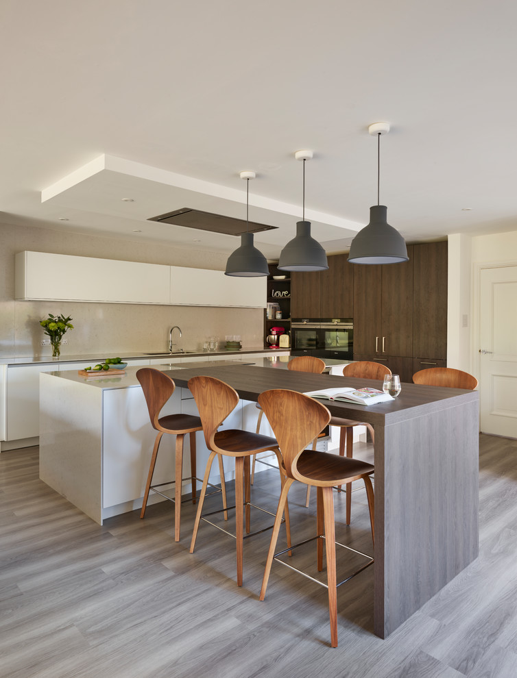 Example of a mid-sized trendy galley light wood floor and gray floor kitchen design in Berkshire with flat-panel cabinets, dark wood cabinets, wood countertops and an island