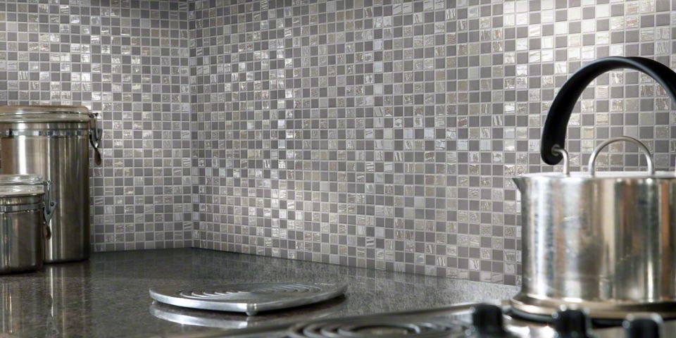 Modern kitchen in Indianapolis with granite worktops, grey splashback, mosaic tiled splashback and stainless steel appliances.