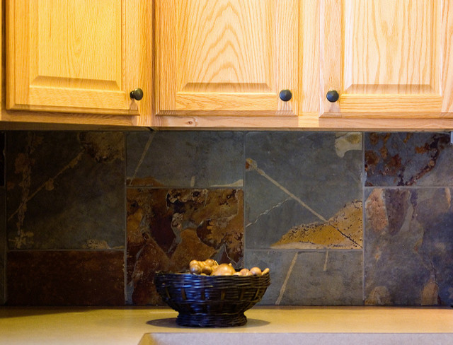 Cette image montre une petite cuisine traditionnelle en bois clair avec un placard avec porte à panneau surélevé, une crédence grise et une crédence en céramique.