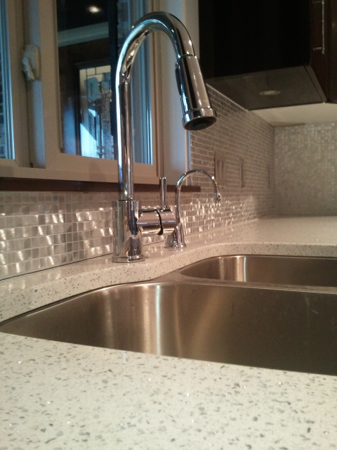 Foto di una cucina minimal di medie dimensioni con lavello a doppia vasca, ante nere, top in vetro riciclato, paraspruzzi bianco, paraspruzzi con piastrelle di metallo e top bianco