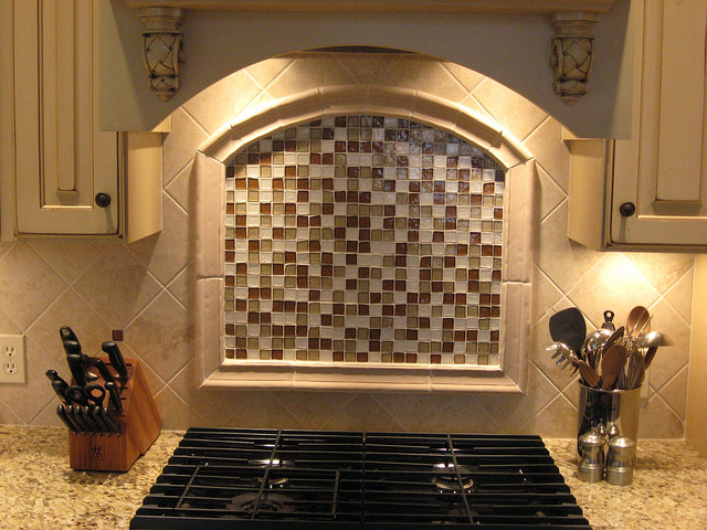 Kitchen - mid-sized traditional kitchen idea in Grand Rapids with raised-panel cabinets, white cabinets, granite countertops, multicolored backsplash, glass tile backsplash and gray countertops