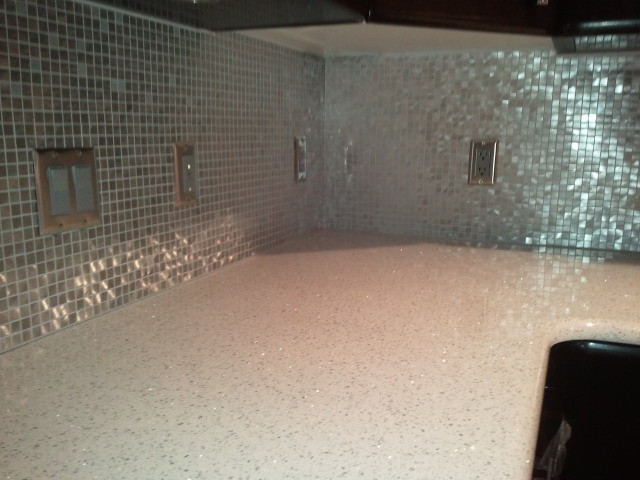 Immagine di una cucina design di medie dimensioni con lavello a doppia vasca, ante nere, top in vetro riciclato, paraspruzzi bianco, paraspruzzi con piastrelle di metallo e top bianco