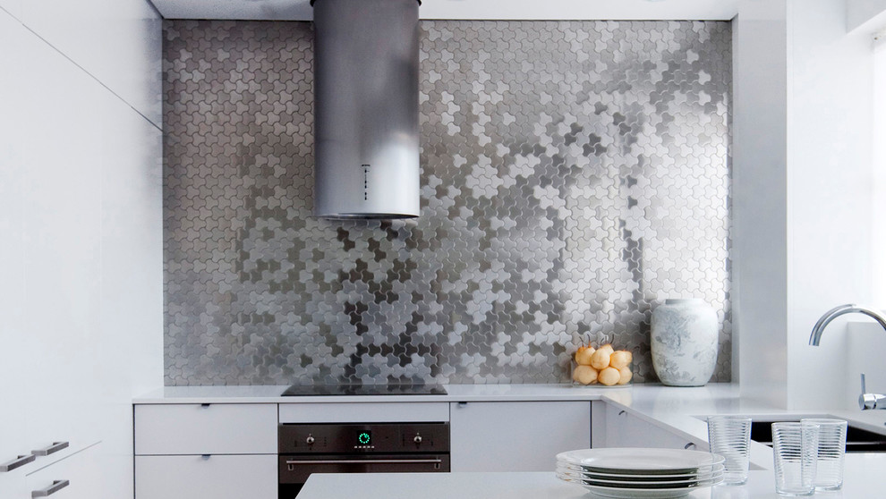 Foto på ett funkis kök, med grått stänkskydd, stänkskydd i metallkakel och rostfria vitvaror