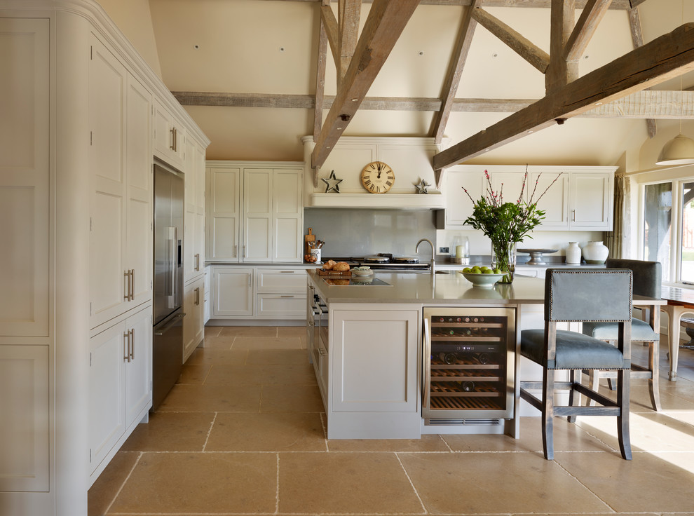 Foto på ett stort lantligt kök, med beige skåp, bänkskiva i koppar, beige stänkskydd, en köksö, luckor med infälld panel, rostfria vitvaror och beiget golv