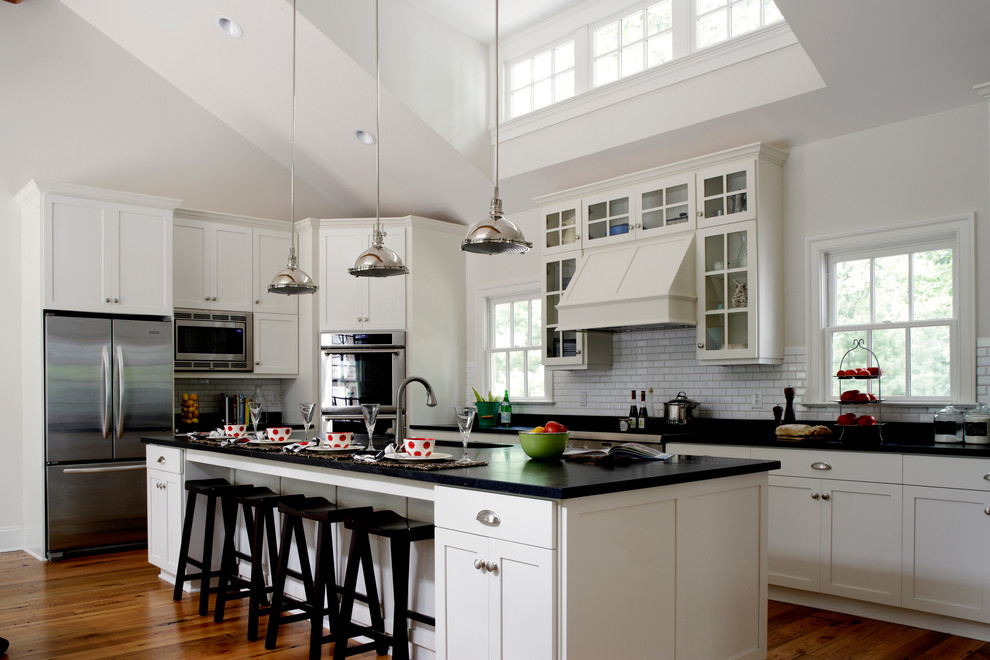 Example of a farmhouse kitchen design in Other with shaker cabinets, white backsplash, subway tile backsplash and stainless steel appliances