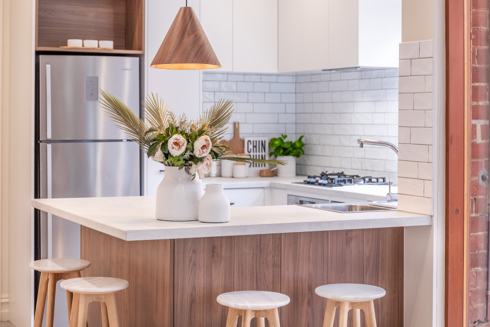 Inspiration for a small contemporary u-shaped cement tile floor and gray floor kitchen remodel in Adelaide with a double-bowl sink, flat-panel cabinets, white cabinets, laminate countertops, white backsplash, subway tile backsplash, stainless steel appliances, a peninsula and gray countertops