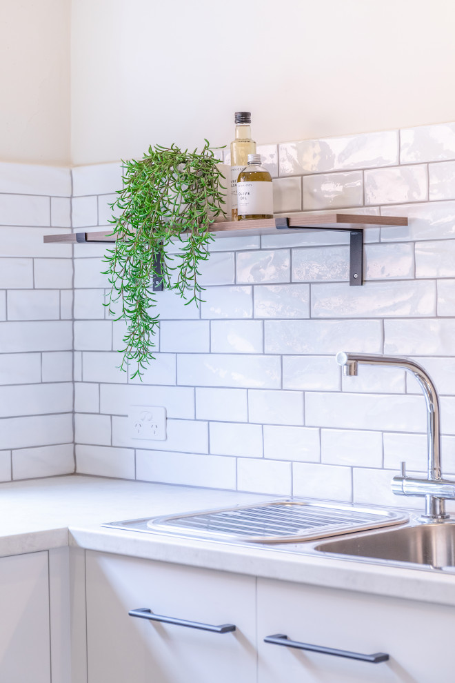 Inspiration for a small contemporary u-shaped kitchen in Adelaide with a double-bowl sink, flat-panel cabinets, white cabinets, laminate countertops, white splashback, metro tiled splashback, stainless steel appliances, cement flooring, a breakfast bar, grey floors and grey worktops.