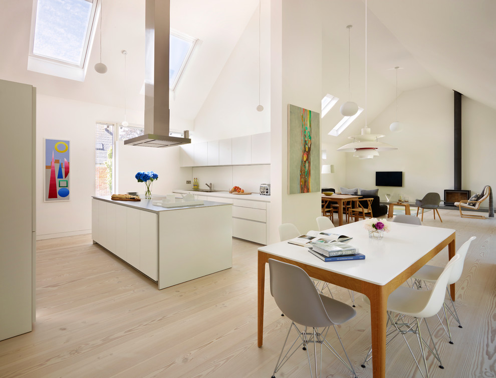 Cette photo montre une cuisine ouverte parallèle tendance de taille moyenne avec un placard à porte plane, des portes de placard blanches, une crédence blanche, parquet clair et îlot.