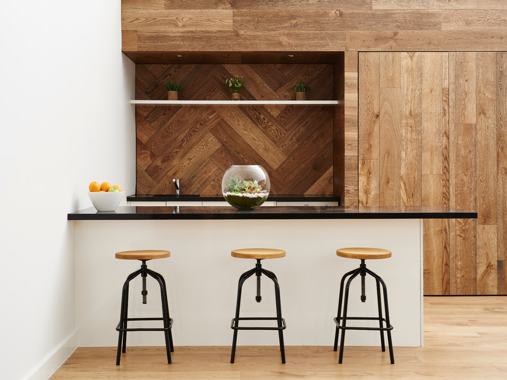 Стильный дизайн: параллельная кухня в современном стиле с техникой под мебельный фасад, светлым паркетным полом и полуостровом - последний тренд