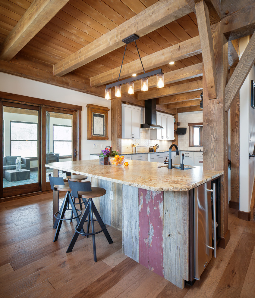 Exemple d'une cuisine montagne avec un évier encastré, un placard à porte shaker, des portes de placard blanches, une crédence blanche, un sol en bois brun, îlot et un plan de travail beige.