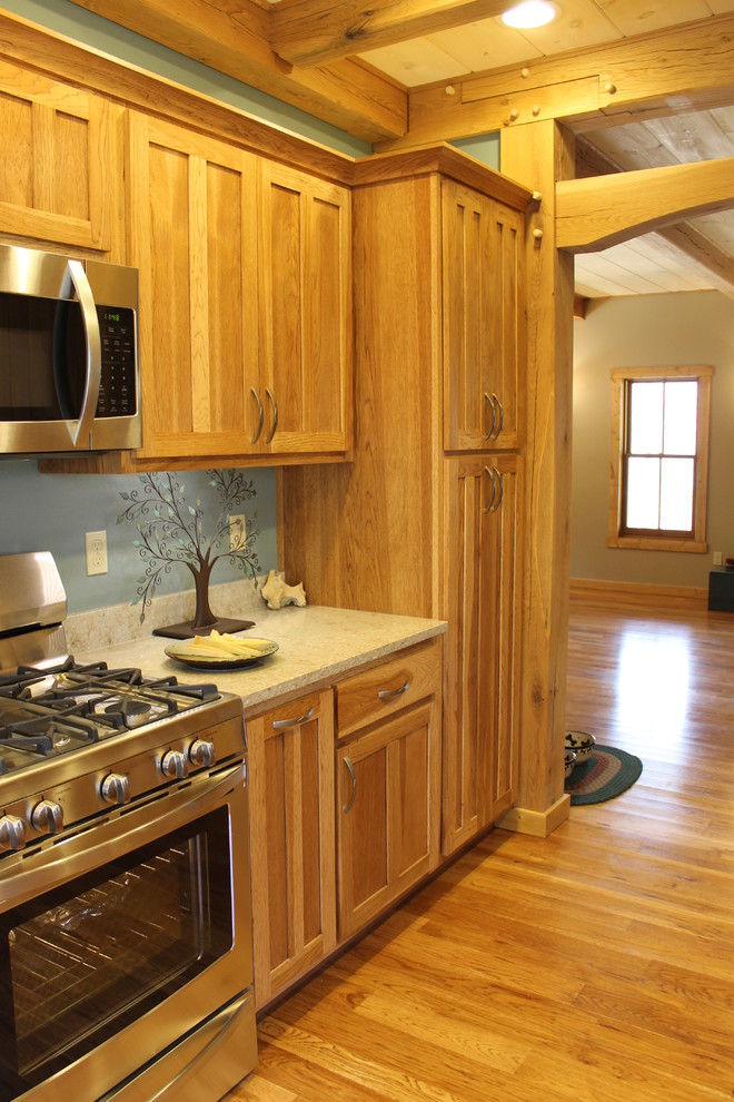 Foto de cocina de estilo americano de tamaño medio con armarios estilo shaker, puertas de armario de madera clara, encimera de granito, electrodomésticos de acero inoxidable y suelo de madera clara