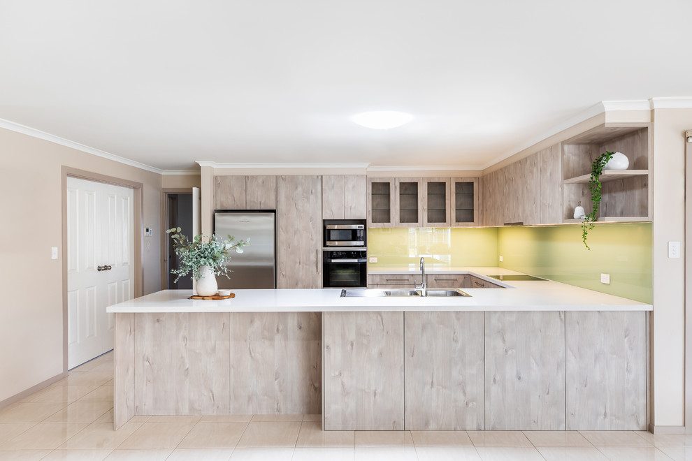 Inspiration for a mid-sized modern u-shaped porcelain tile and white floor kitchen pantry remodel in Adelaide with a double-bowl sink, flat-panel cabinets, light wood cabinets, quartz countertops, green backsplash, glass sheet backsplash, stainless steel appliances, a peninsula and white countertops
