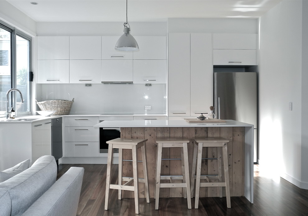 Design ideas for a medium sized modern kitchen/diner in Melbourne with white splashback, glass sheet splashback, stainless steel appliances, medium hardwood flooring, an island, engineered stone countertops, a double-bowl sink, flat-panel cabinets and white cabinets.