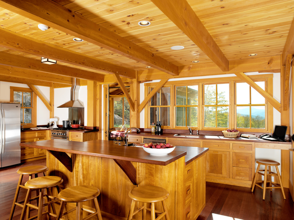 Foto på ett rustikt kök, med en undermonterad diskho, skåp i shakerstil, skåp i mellenmörkt trä, träbänkskiva, fönster som stänkskydd, rostfria vitvaror, mörkt trägolv, en köksö och brunt golv
