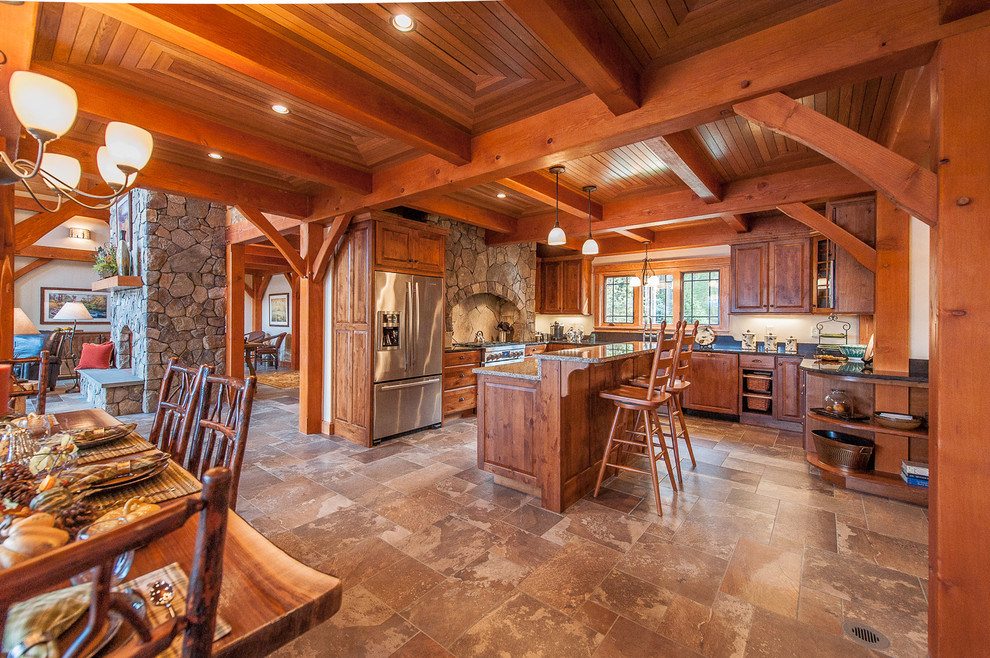 Exempel på ett rustikt kök, med luckor med upphöjd panel, skåp i mellenmörkt trä, rostfria vitvaror, en köksö och brunt golv