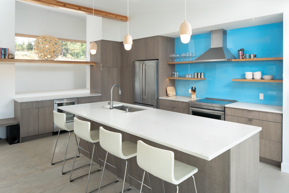 Foto di una grande cucina contemporanea con lavello sottopiano, ante lisce, ante grigie, paraspruzzi blu, paraspruzzi con lastra di vetro, elettrodomestici in acciaio inossidabile, pavimento grigio e top bianco