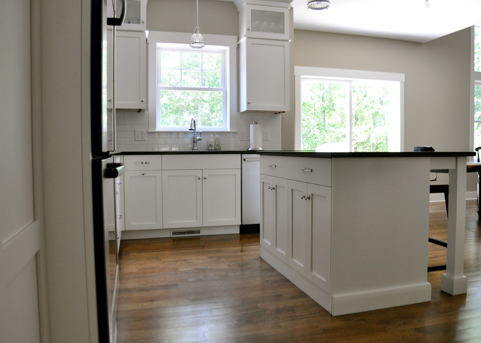 Inspiration for a transitional l-shaped medium tone wood floor open concept kitchen remodel in Grand Rapids with shaker cabinets, white cabinets, granite countertops, white backsplash, subway tile backsplash, stainless steel appliances, an island and a double-bowl sink