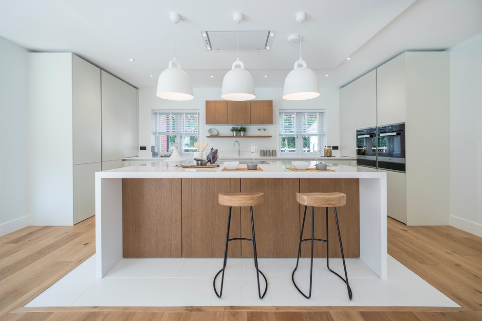 Idéer för ett modernt u-kök, med släta luckor, vita skåp, mellanmörkt trägolv, en köksö och brunt golv