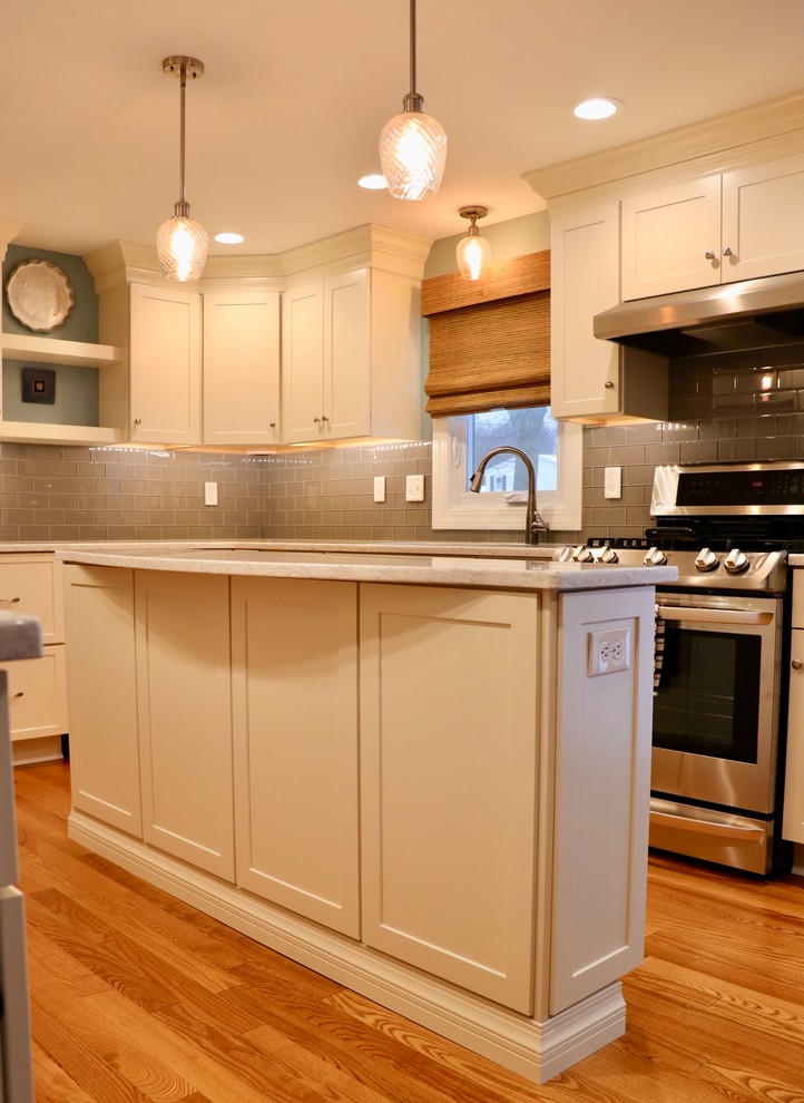 Idéer för att renovera ett stort vintage vit vitt kök, med en dubbel diskho, skåp i shakerstil, vita skåp, bänkskiva i kvarts, grått stänkskydd, stänkskydd i tunnelbanekakel, rostfria vitvaror, mellanmörkt trägolv, en köksö och orange golv