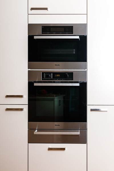 Immagine di una cucina minimal di medie dimensioni con lavello integrato, ante lisce, ante grigie, top in superficie solida e elettrodomestici in acciaio inossidabile
