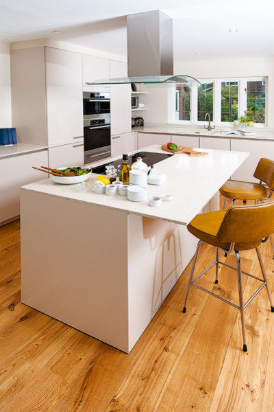 This is an example of a medium sized contemporary u-shaped kitchen/diner in Hampshire with an integrated sink, flat-panel cabinets, grey cabinets, composite countertops, stainless steel appliances and an island.