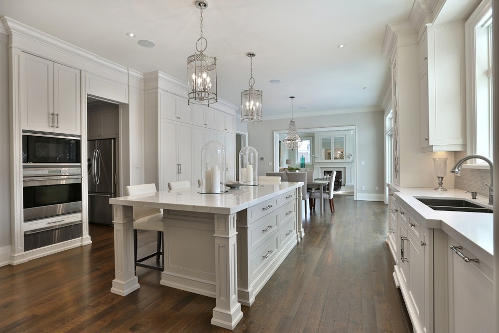 Eat-in kitchen - traditional u-shaped medium tone wood floor eat-in kitchen idea in Toronto with an undermount sink, beaded inset cabinets, white cabinets, quartz countertops, gray backsplash, glass tile backsplash, paneled appliances and an island