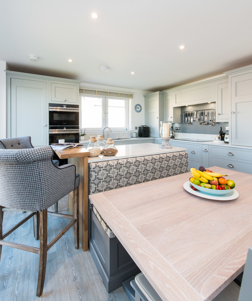 Inspiration for a medium sized classic l-shaped kitchen/diner in Edinburgh with an integrated sink, shaker cabinets, grey cabinets, quartz worktops, grey splashback, glass sheet splashback, stainless steel appliances, laminate floors, an island, grey floors and white worktops.