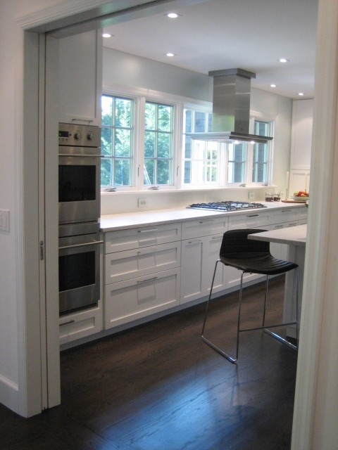 Inspiration för stora moderna kök, med en dubbel diskho, luckor med infälld panel, vita skåp, bänkskiva i kvartsit, stänkskydd med metallisk yta, glaspanel som stänkskydd, rostfria vitvaror, mörkt trägolv och en köksö