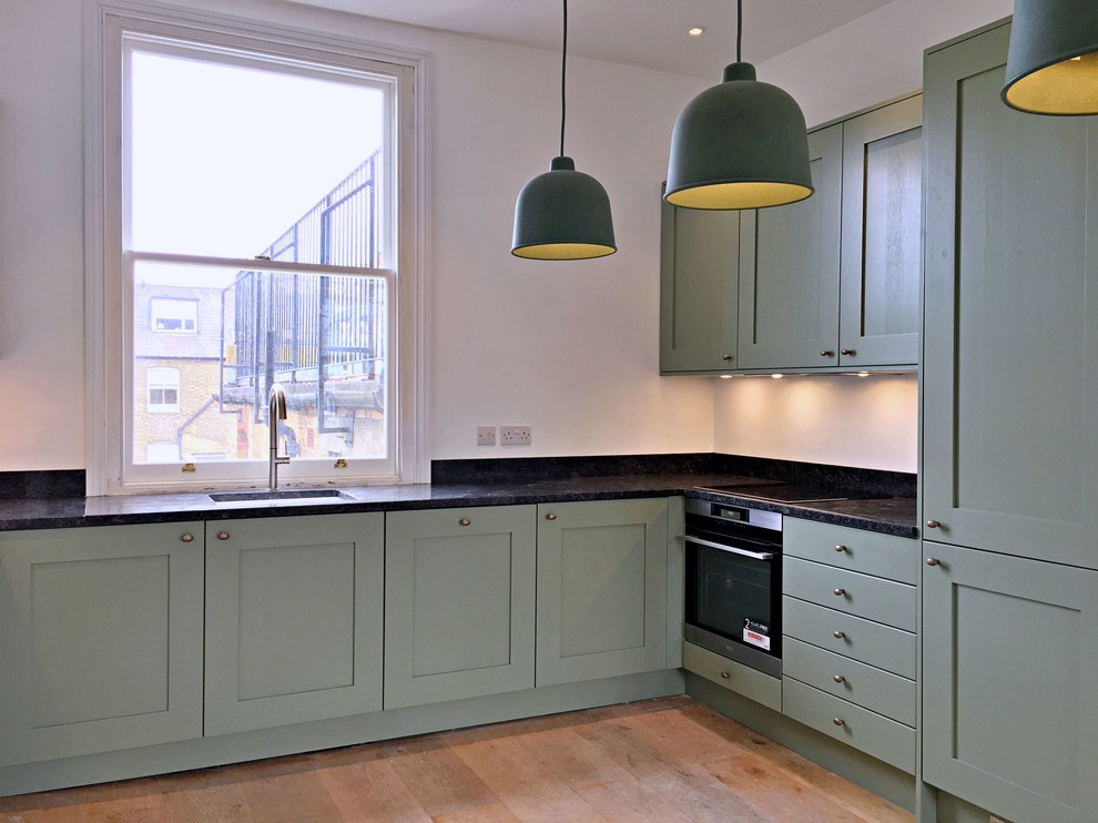 Inspiration for a medium sized classic l-shaped kitchen/diner in London with shaker cabinets, green cabinets, quartz worktops, black appliances, no island and black worktops.