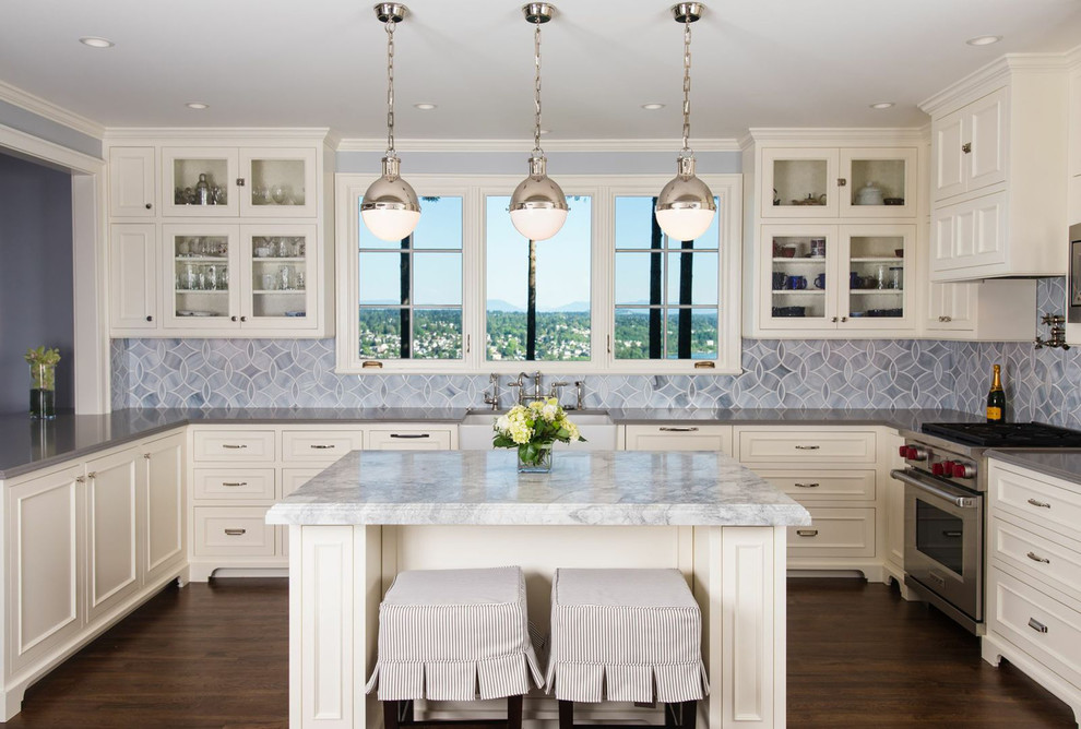 Elegant kitchen photo in Seattle with glass-front cabinets, stainless steel appliances, blue backsplash, white cabinets and quartzite countertops