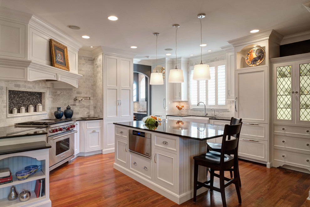 Inspiration for a transitional medium tone wood floor enclosed kitchen remodel in Chicago with a farmhouse sink, beaded inset cabinets, white cabinets, granite countertops, white backsplash, stone tile backsplash, stainless steel appliances and an island