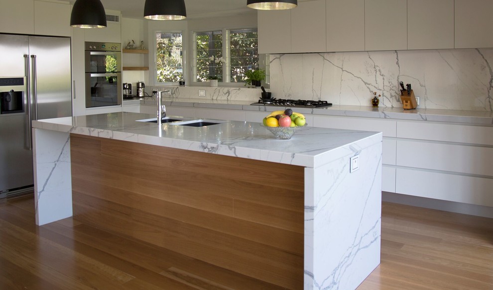 Esempio di una cucina contemporanea con lavello sottopiano, ante lisce, ante bianche, top in marmo, elettrodomestici in acciaio inossidabile e parquet chiaro