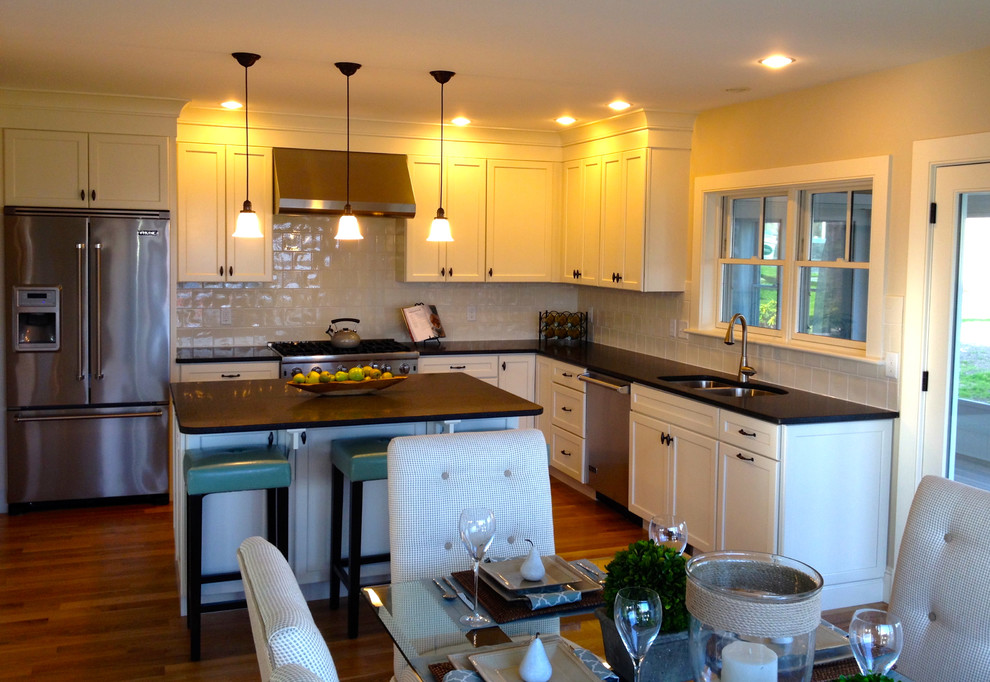 Inspiration for a mid-sized timeless l-shaped medium tone wood floor eat-in kitchen remodel in Boston with shaker cabinets, an island, white cabinets, marble countertops, white backsplash, porcelain backsplash, an undermount sink and stainless steel appliances