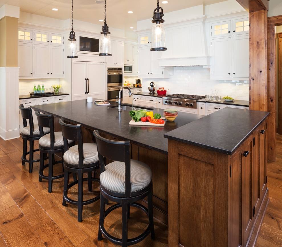 Large elegant l-shaped medium tone wood floor and brown floor open concept kitchen photo in Minneapolis with an undermount sink, flat-panel cabinets, white cabinets, granite countertops, white backsplash, ceramic backsplash, paneled appliances and an island