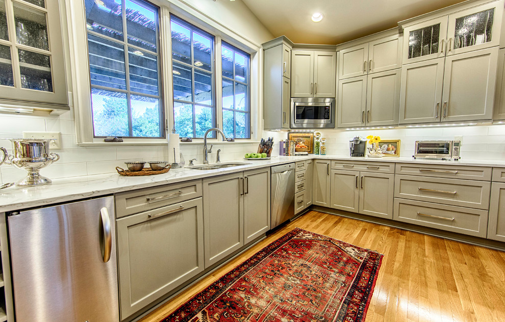 Example of a large classic u-shaped light wood floor open concept kitchen design in Birmingham with a double-bowl sink, shaker cabinets, gray cabinets, quartz countertops, white backsplash, subway tile backsplash, stainless steel appliances and no island