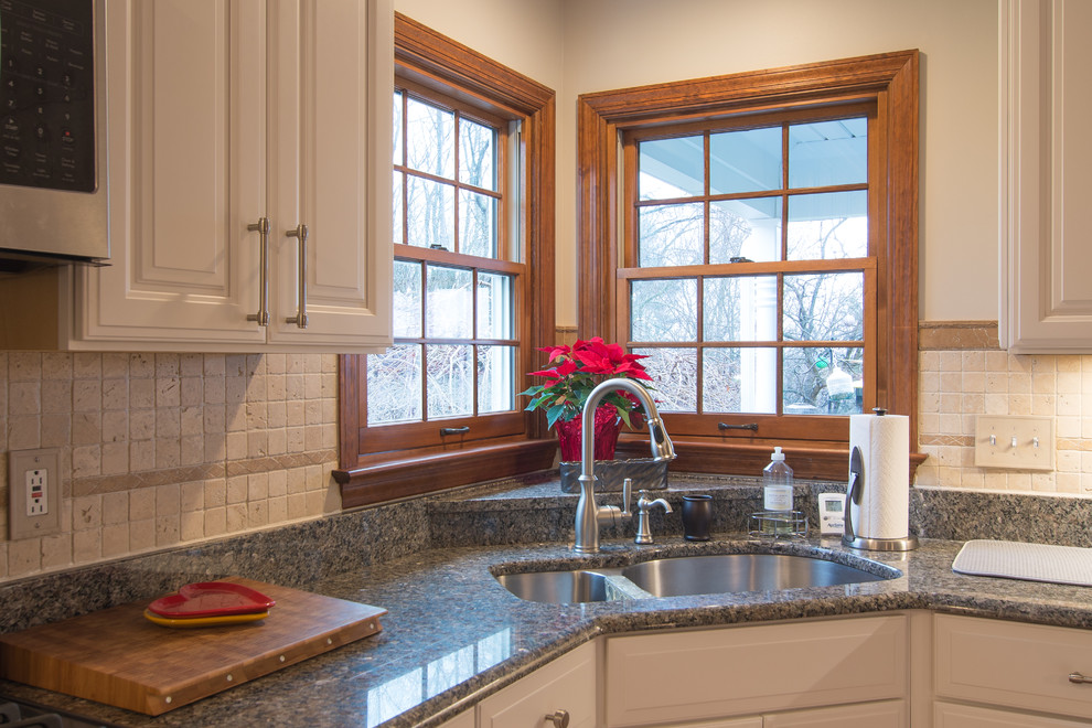 Klassische Küche mit weißen Schränken, Granit-Arbeitsplatte, braunem Holzboden und Kücheninsel in Sonstige