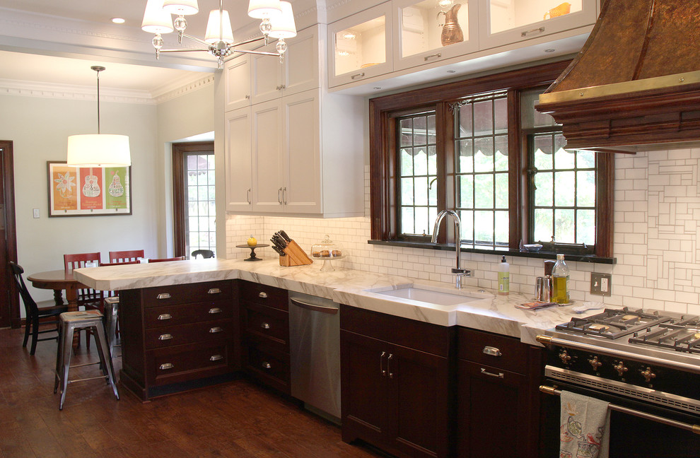 Foto på ett mellanstort vintage kök, med en undermonterad diskho, luckor med infälld panel, skåp i mörkt trä, marmorbänkskiva, vitt stänkskydd, stänkskydd i porslinskakel, rostfria vitvaror, mellanmörkt trägolv, en halv köksö och brunt golv