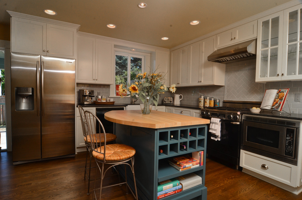 Rustikale Küche mit Landhausspüle, Schrankfronten im Shaker-Stil, weißen Schränken, Küchenrückwand in Grau, Rückwand aus Porzellanfliesen, Küchengeräten aus Edelstahl, braunem Holzboden und Kücheninsel in Portland