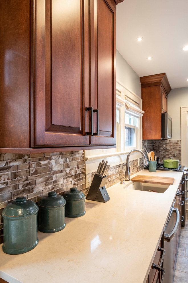 Example of a small classic galley ceramic tile and brown floor enclosed kitchen design in Indianapolis with an undermount sink, raised-panel cabinets, medium tone wood cabinets, quartz countertops, multicolored backsplash, glass tile backsplash, colored appliances, no island and white countertops