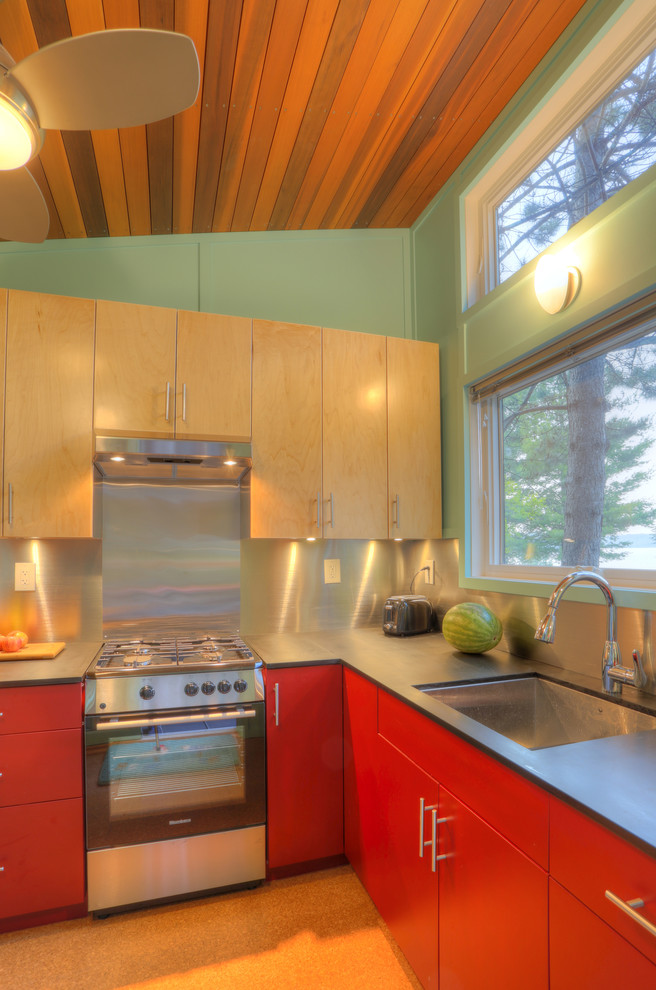 Inredning av ett modernt litet kök, med en undermonterad diskho, släta luckor, röda skåp, bänkskiva i koppar, stänkskydd med metallisk yta, rostfria vitvaror och korkgolv