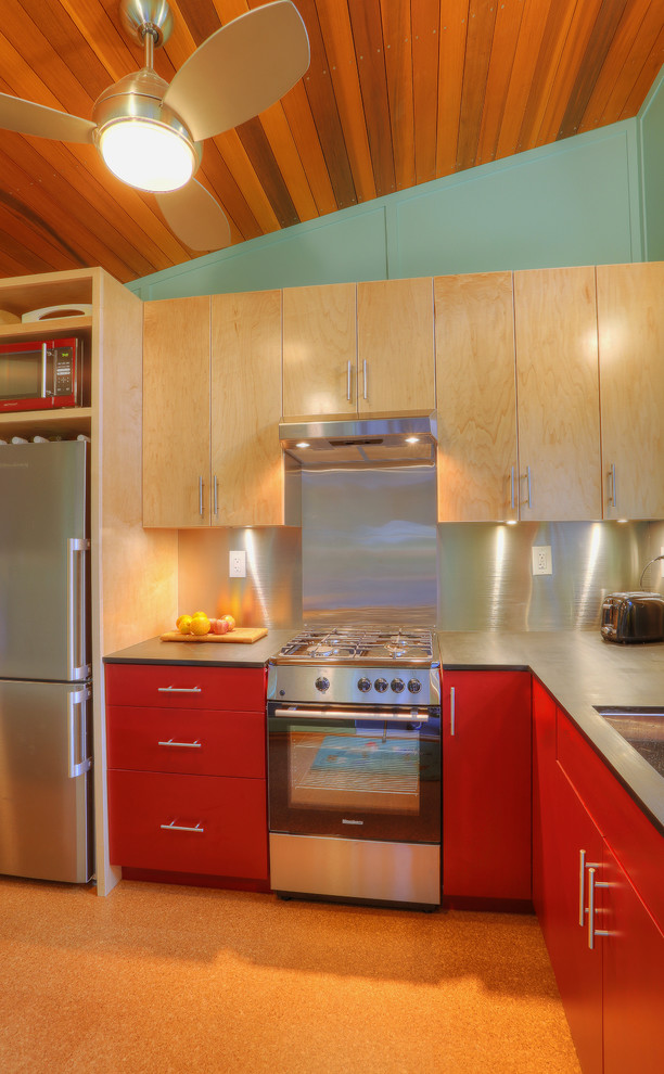 Modern inredning av ett litet kök, med en undermonterad diskho, släta luckor, röda skåp, bänkskiva i koppar, stänkskydd med metallisk yta, rostfria vitvaror och korkgolv