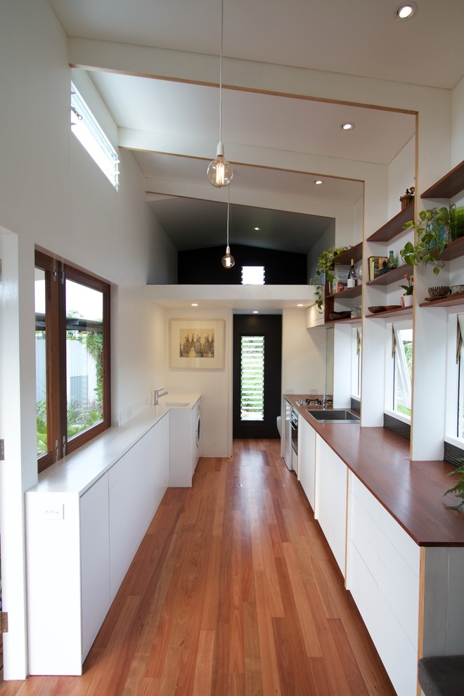 Ejemplo de cocina comedor minimalista pequeña sin isla con puertas de armario blancas, encimera de madera y suelo de madera en tonos medios