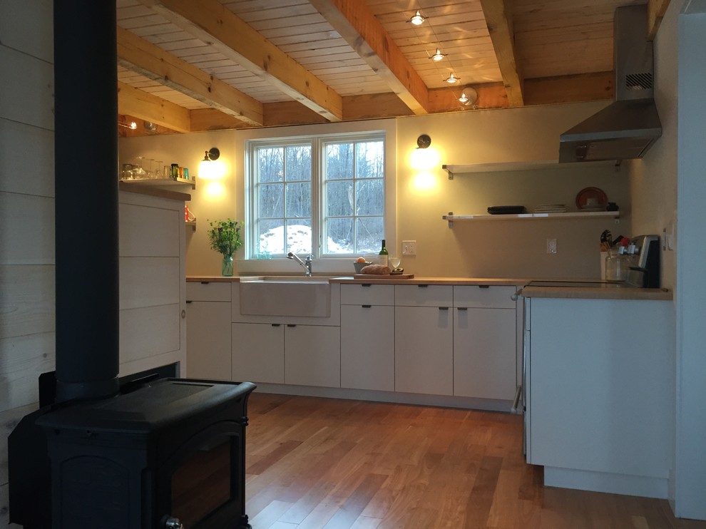 Immagine di una cucina scandinava chiusa e di medie dimensioni con lavello stile country, ante lisce, ante bianche, top in legno, elettrodomestici in acciaio inossidabile e parquet chiaro