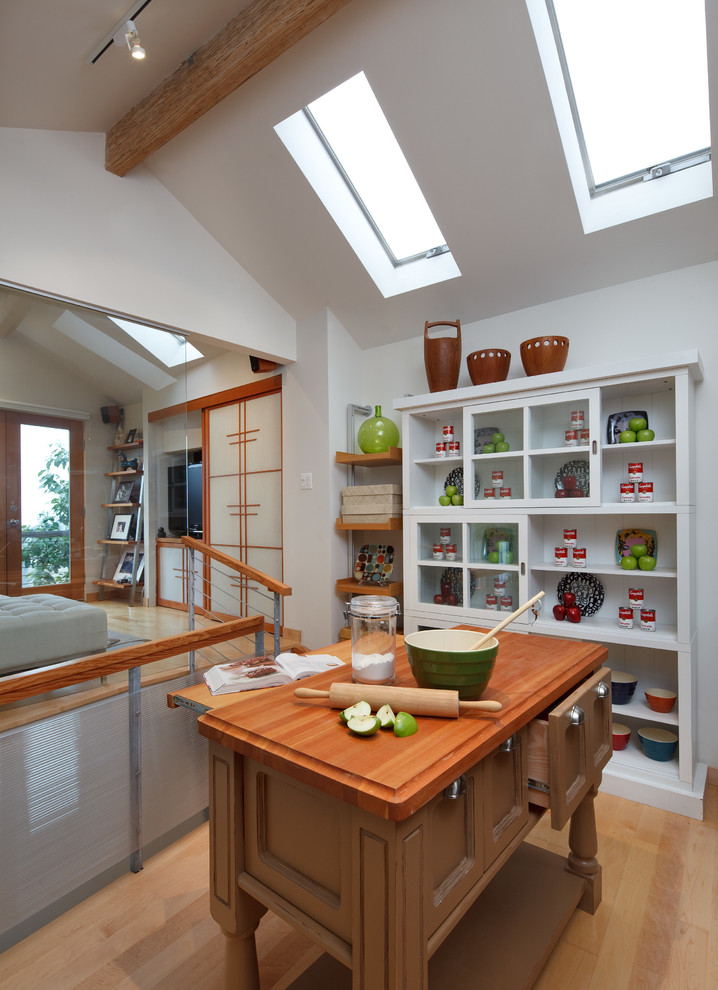 Foto de cocina actual de tamaño medio con armarios abiertos, puertas de armario blancas, encimera de madera, una isla, suelo de madera clara y suelo beige