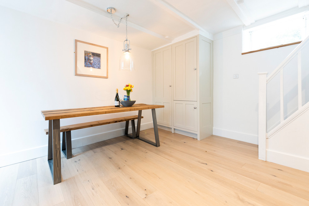 Moderne Küche mit profilierten Schrankfronten, blauen Schränken, Granit-Arbeitsplatte, Küchenrückwand in Weiß, Küchengeräten aus Edelstahl, braunem Holzboden und grauer Arbeitsplatte in Cornwall
