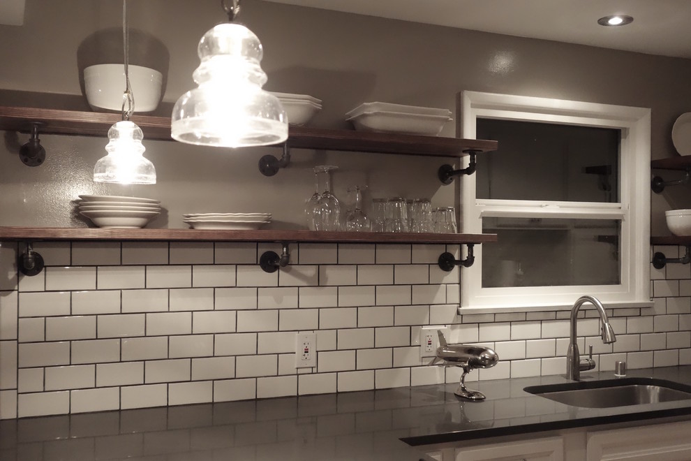 Bild på ett litet industriellt kök, med en undermonterad diskho, luckor med infälld panel, vita skåp, bänkskiva i kvarts, vitt stänkskydd, stänkskydd i keramik, rostfria vitvaror, mellanmörkt trägolv och en halv köksö