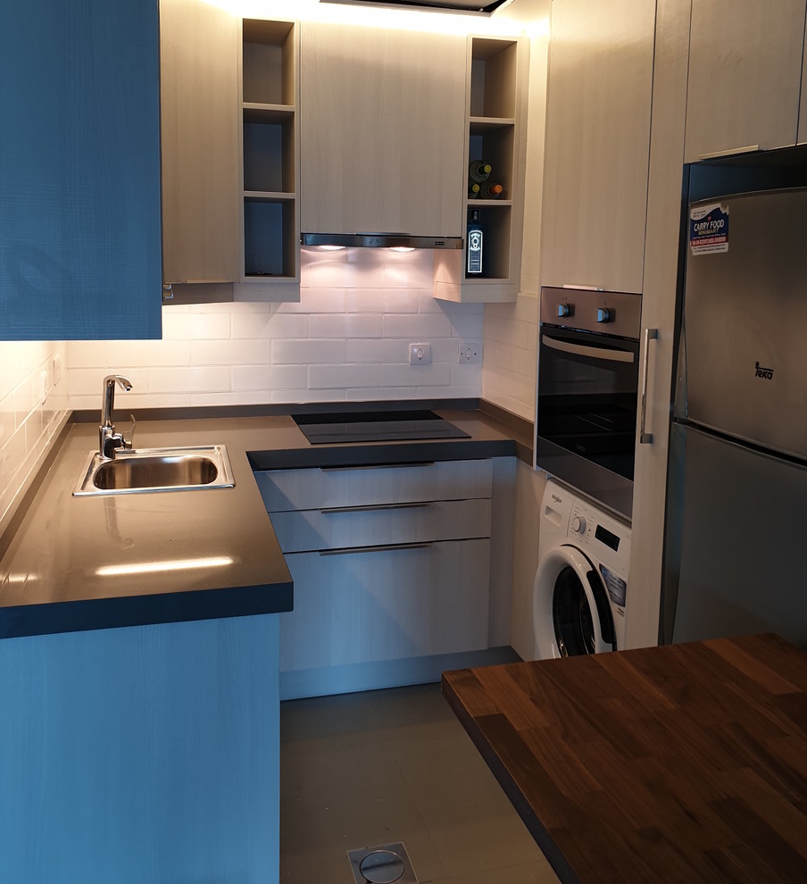 Modern inredning av ett litet grå grått kök, med en enkel diskho, släta luckor, vita skåp, granitbänkskiva, vitt stänkskydd, stänkskydd i tunnelbanekakel och rostfria vitvaror