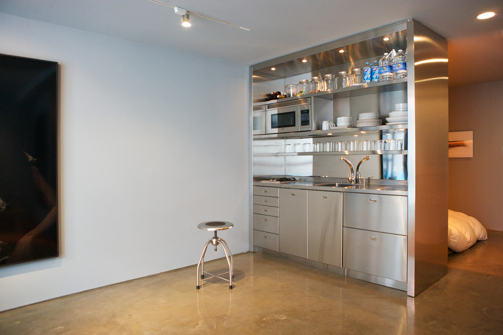 Cette image montre une cuisine américaine linéaire design en inox avec un évier intégré, un placard à porte plane, un plan de travail en inox, une crédence miroir et un électroménager en acier inoxydable.