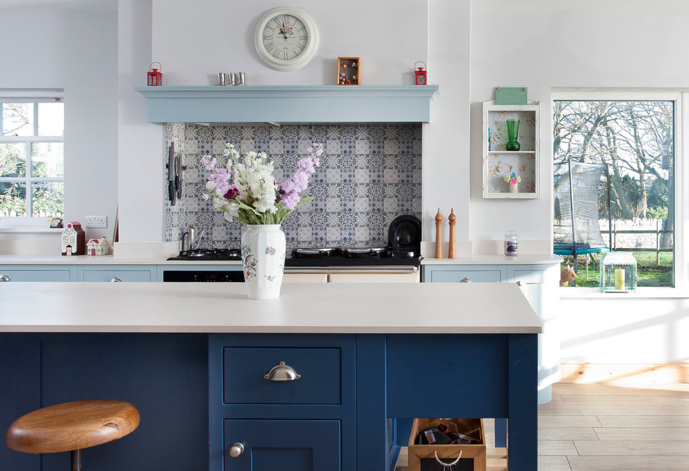 Foto på ett mellanstort lantligt kök, med en undermonterad diskho, skåp i shakerstil, blå skåp, bänkskiva i kvarts, blått stänkskydd, stänkskydd i keramik, integrerade vitvaror, klinkergolv i keramik, en köksö och brunt golv